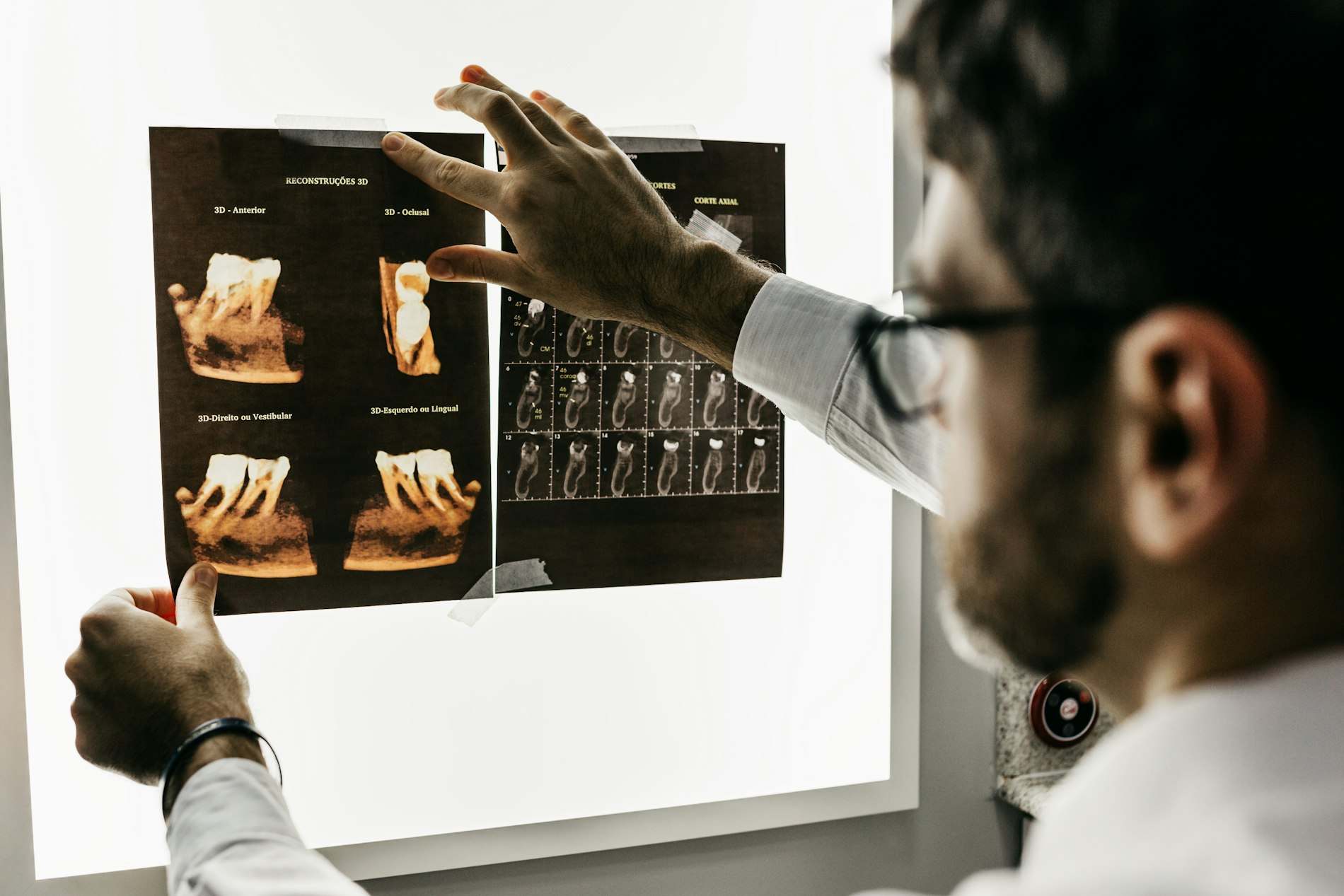 Dentista analisando radiografias dentárias num painel iluminado