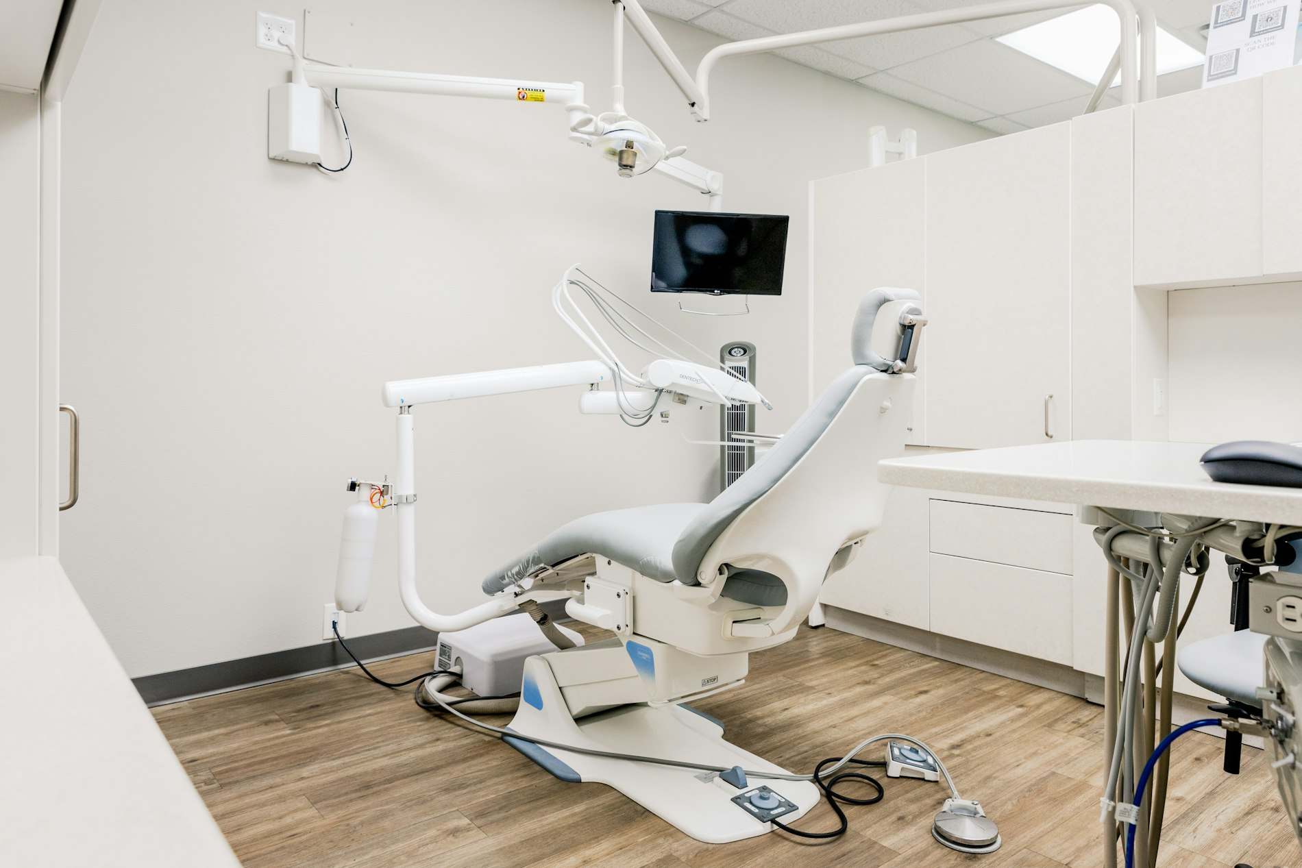 Sala de atendimento com cadeira, bancada e armários claros